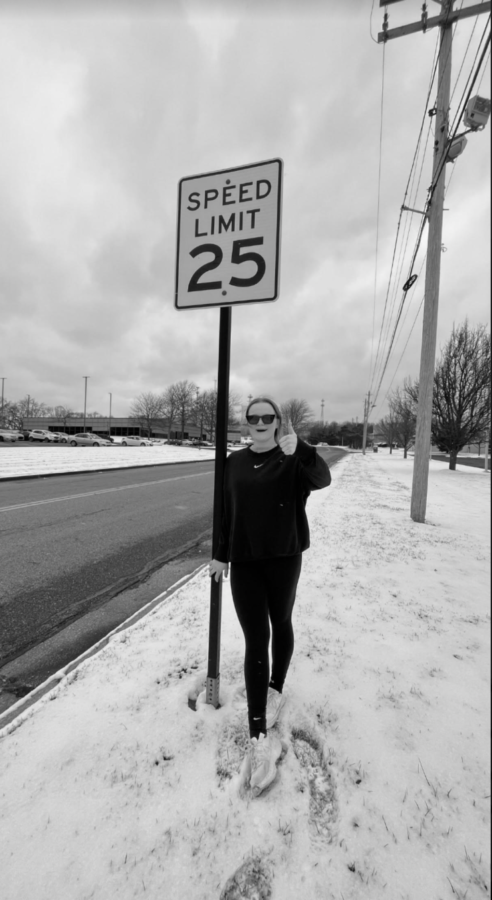 Mallory Gearhart poses under the Tabs Drive speed limit sign.